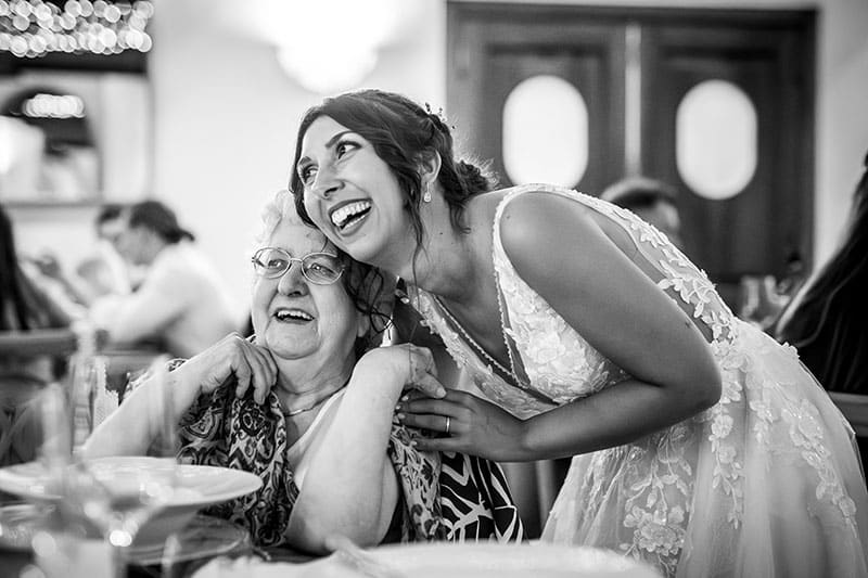 sposa che abbraccia la nonna durante il pranzo nuziale. Scatto di Mario Amelio Fotografo di matrimonio reportage.
