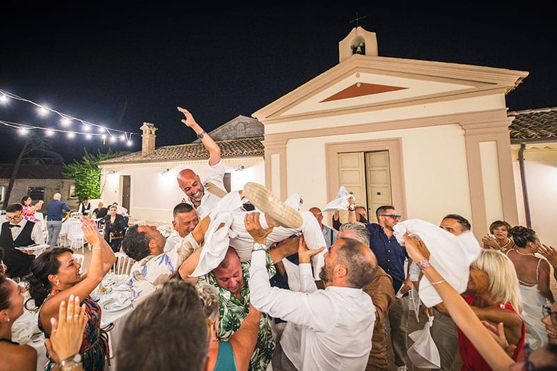 invitati che lanciano in aria lo sposo. Scatto di Mario Amelio Fotografo di matrimonio reportage.