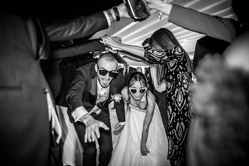 sposi che passano sotto al ponte di persone durante i balli. Scatto di Mario Amelio Fotografo di matrimonio reportage.