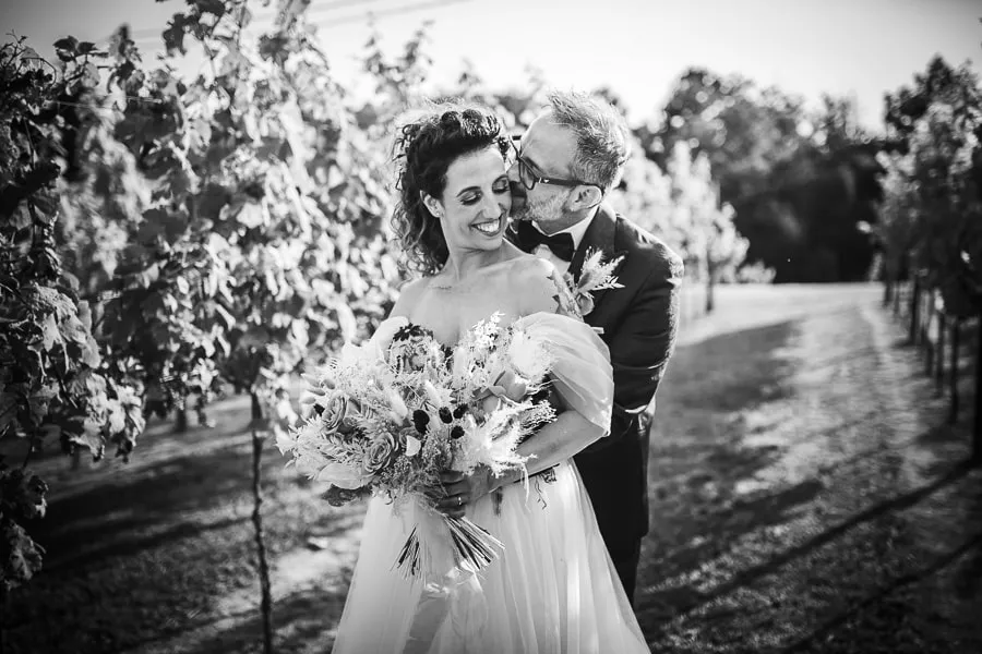 Sposi tra i vigneti de La Corte e il Sogno a Bergamo, mentre si scambiano un bacio romantico immortalati dal fotografo matrimonio bergamo.