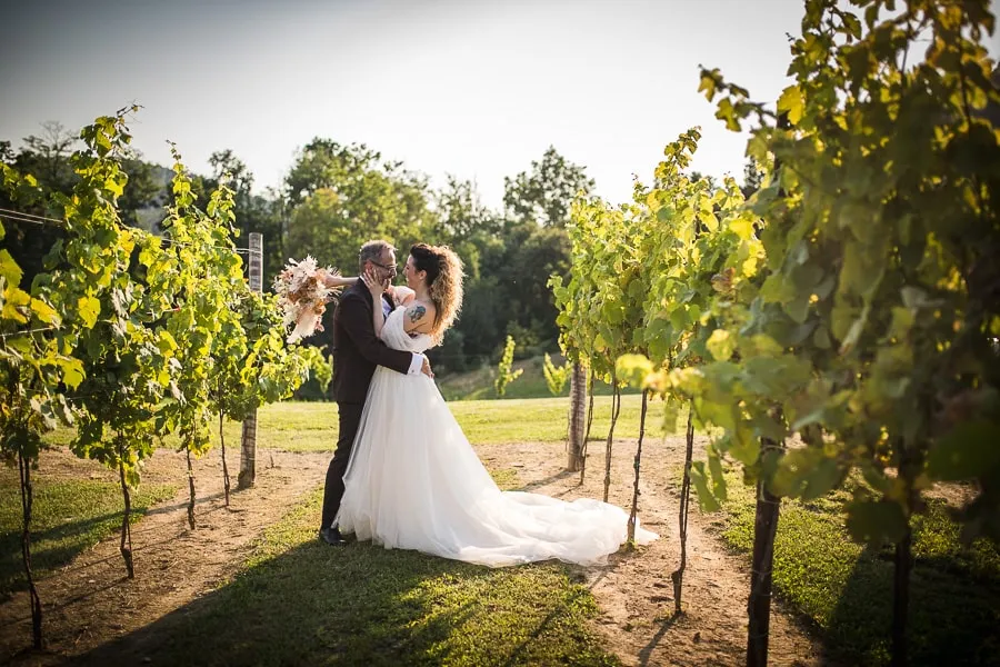 Sposi nel vigneto de La Corte e il Sogno a Bergamo, in un abbraccio romantico immerso nella natura. Scatto di fotografo matrimonio bergamo.