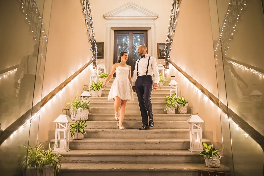 Gli sposi mano nella mano scendono le scale di una villa elegante durante il matrimonio