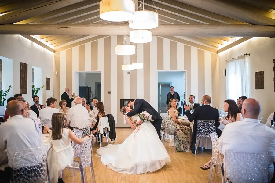 Un bacio tra gli sposi nella sala di Borgo Santa Giulia sposi mentre si scambiano un bacio appassionato nella sala ricevimenti di Borgo Santa Giulia, tra gli applausi degli invitati