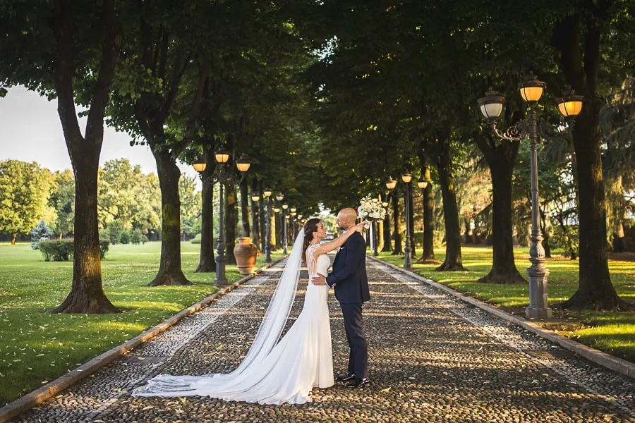 Sposi nel viale alberato di Villa Valenca al tramonto Fotografo matrimonio Brescia cattura gli sposi nel romantico viale alberato di Villa Valenca, avvolti dalla luce calda del tramonto