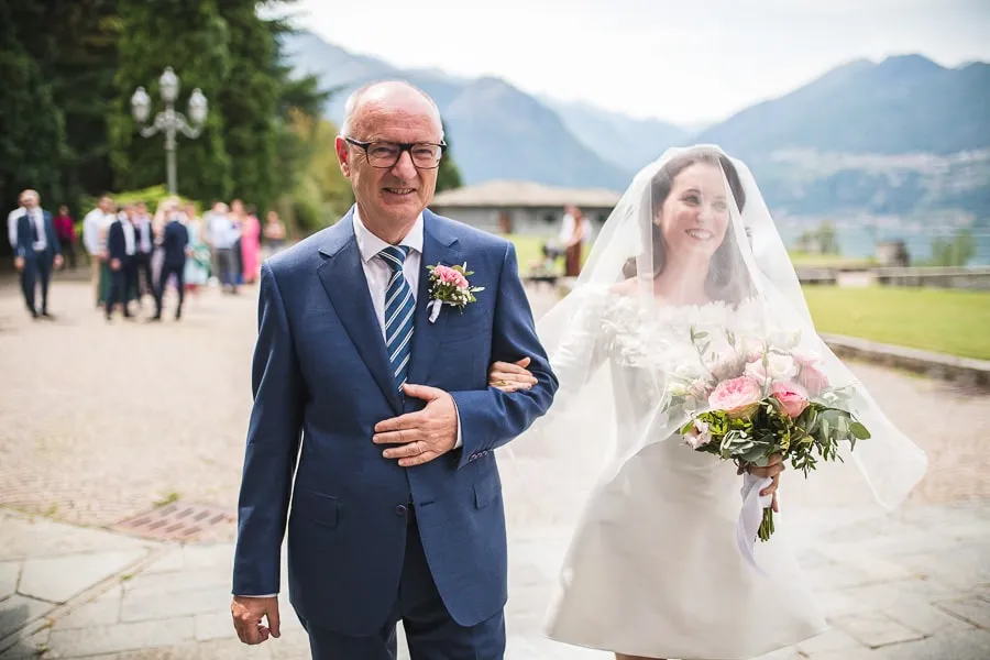 L'arrivo della sposa in riva al Lago di Como La sposa arriva raggiante al braccio del padre con il Lago di Como sullo sfondo