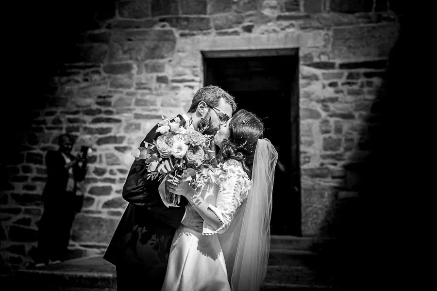 Il bacio degli sposi fuori dalla chiesa Sposi che si baciano fuori dalla chiesa dopo la cerimonia, con il bouquet in primo piano