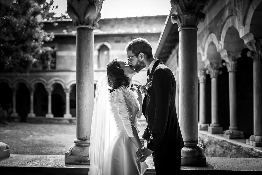 Un bacio nel chiostro: romanticismo senza tempo Sposi che si baciano in un suggestivo chiostro antico, immersi in un'atmosfera romantica