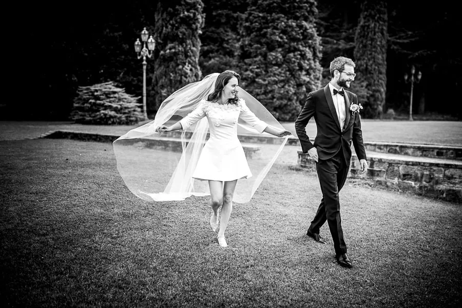 Un matrimonio alternativo: sposa in abito corto sul Lago di Como Fotografo matrimonio Como cattura la sposa in abito corto mentre cammina sorridente con lo sposo in un giardino.
