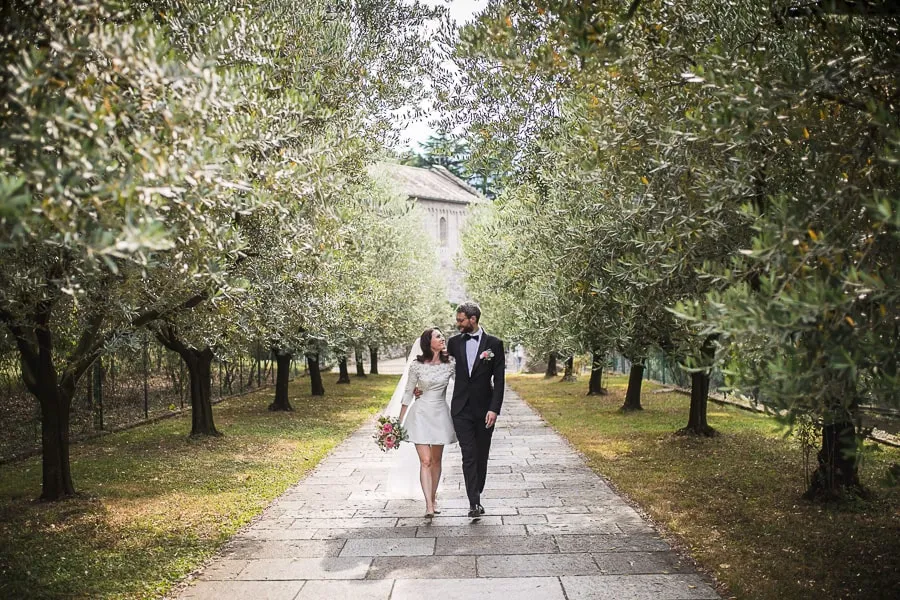 Passeggiata tra gli ulivi all'Abbazia di Piona: un matrimonio dal fascino naturale Fotografo matrimonio Como ritrae gli sposi che passeggiano tra gli ulivi dell'Abbazia di Piona