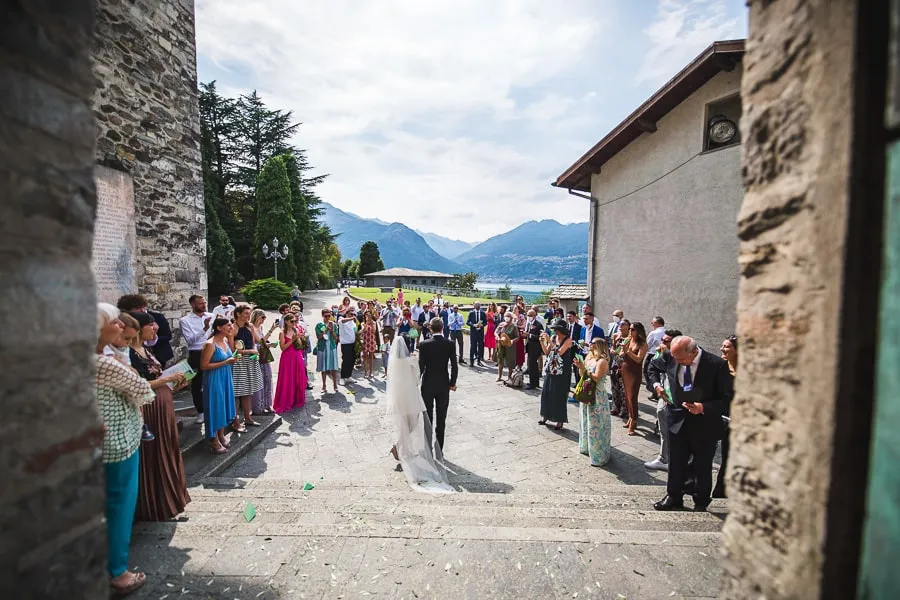 Uscita degli sposi dalla chiesa all'Abbazia di Piona Fotografo matrimonio Como cattura l'uscita degli sposi dalla chiesa dell'Abbazia di Piona, accolti dagli invitati
