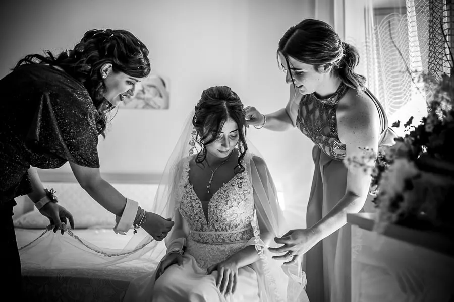 La sposa viene aiutata dalle amiche nei preparativi, un momento intimo da non trascurare quando si tratta di scegliere fotografo matrimonio Lamezia Terme