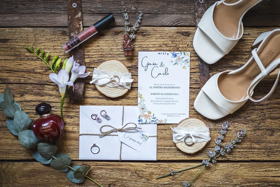 Stationery con inviti, fedi, scarpe e dettagli floreali in stile country chic per il servizio fotografico matrimonio Bergamo.