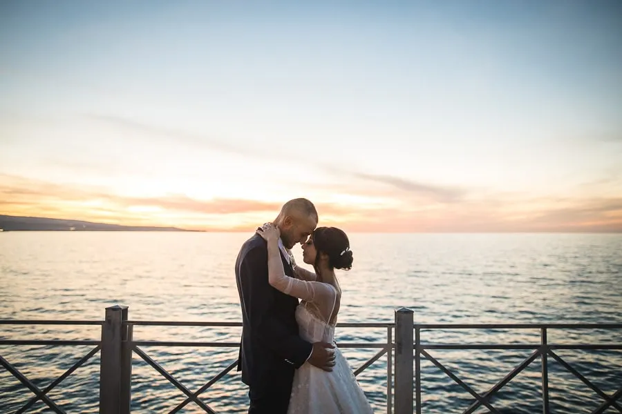 Sposi si abbracciano al tramonto sul mare grazie al timing perfetto dalla collaborazione fotografo wedding planner