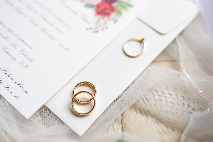 Fedi nuziali e invito di matrimonio posati su un velo, un dettaglio spesso trascurato tra gli errori di fotografia matrimonio.