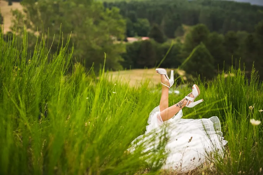 Sposa sdraiata nell’erba con le gambe alzate e scarpe bianche, esempio di spontaneità gestita con professionalità nella gestione imprevisti matrimonio.
