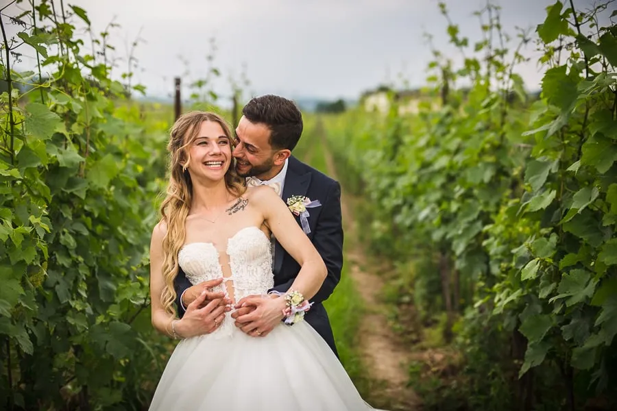 Coppia di sposi sorride tra i vigneti, esempio di servizio realizzato considerando il prezzo fotografo matrimonio Brescia