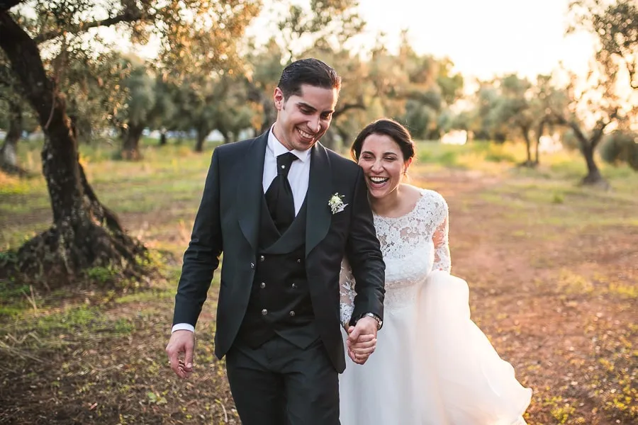 Sposi che ridono e camminano tra gli ulivi a Lamezia Terme, una scena spontanea che valorizza il prezzo fotografo matrimonio Lamezia Terme