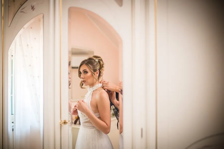 La sposa si prepara davanti allo specchio durante i preparativi, in perfetto stile reportage matrimonio Brescia